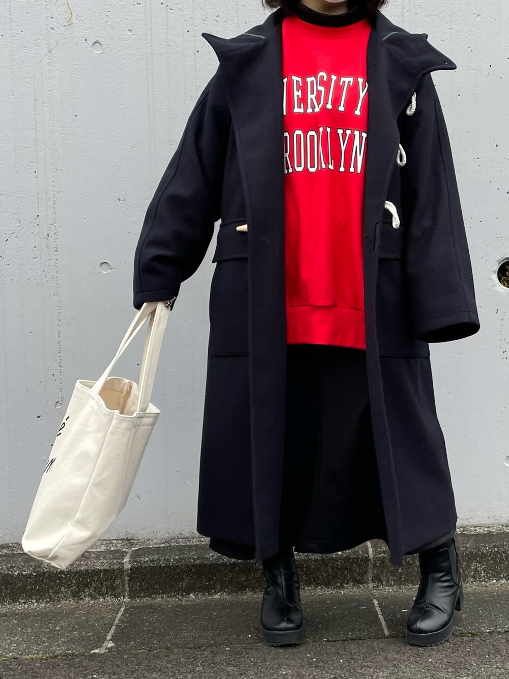 レッド系のスウェット、ブルー系のダッフルコート、ホワイト系のトートバッグを着用したレディースの冬コーディネートの2枚目の写真