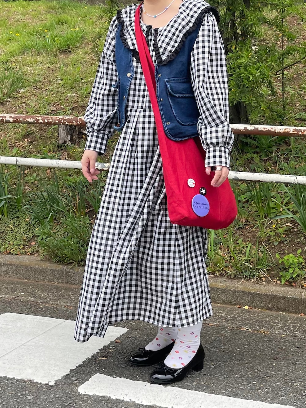 レッド系のショルダーバッグ、シルバー系のピアス（両耳用）を着用したレディースの春コーディネートの3枚目の写真