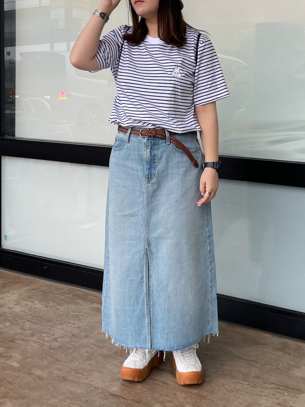 ホワイト系のTシャツ/カットソー、ブルー系のデニムスカート、ホワイト系のスニーカーを着用したレディースの夏コーディネートの2枚目の写真