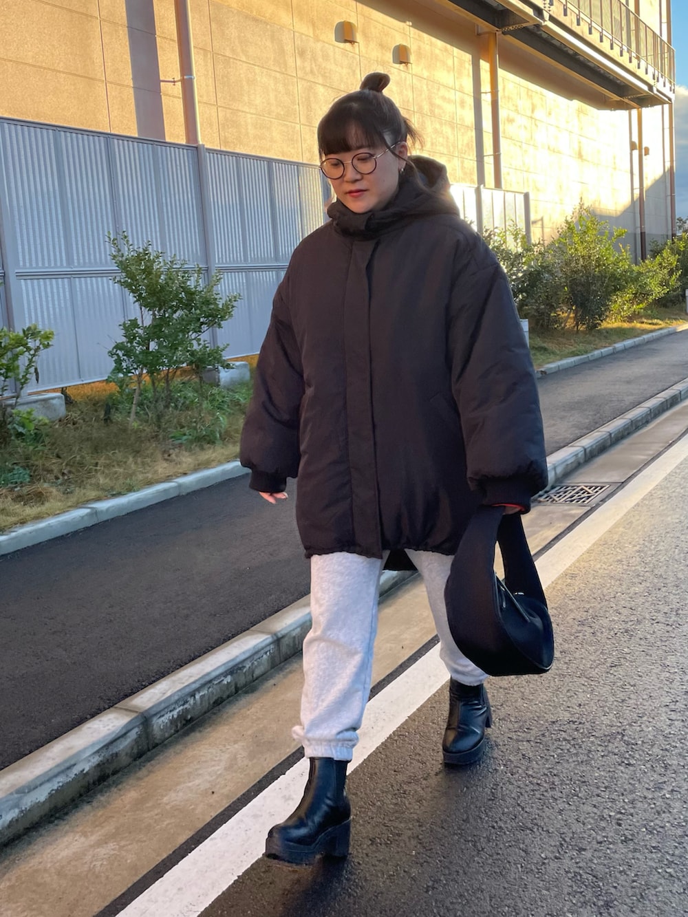 ブラック系のハンドバッグ、ホワイト系のスウェットパンツ、ブラック系のブーツを着用したレディースの冬コーディネートの2枚目の写真