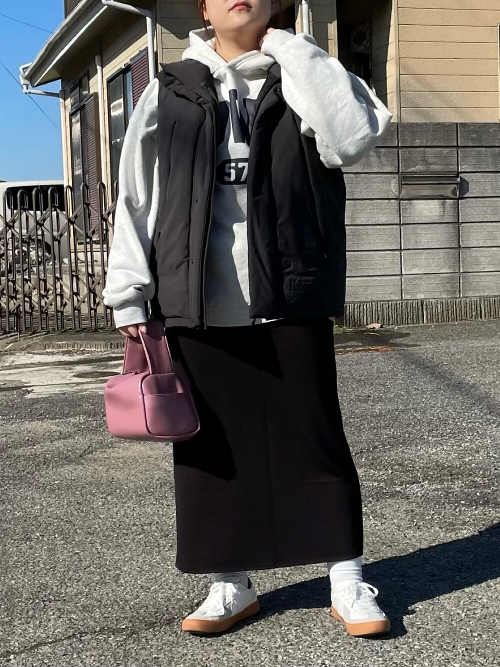 ブラック系のダウンベスト、ベージュ系のパーカー、ピンク系のボストンバッグを着用したレディースの冬コーディネートの2枚目の写真