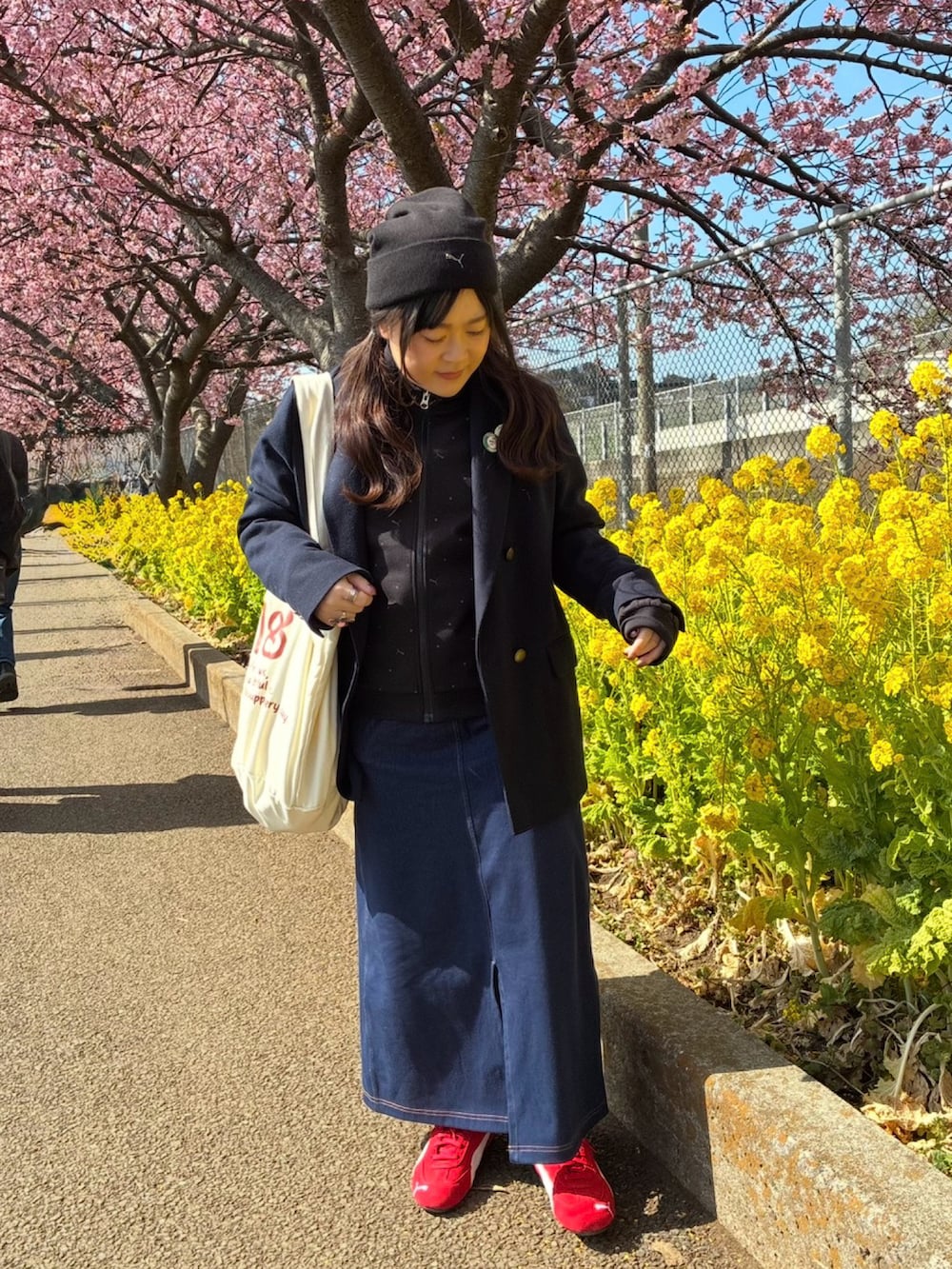 ブラック系のジャージ、ブルー系のスカート、レッド系のスニーカーを着用したレディースの春コーディネートの2枚目の写真