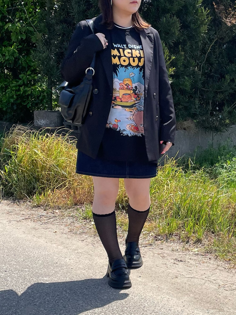 ブラック系のテーラードジャケット、ブラック系のTシャツ/カットソー、ブルー系のデニムスカートを着用したレディースの春コーディネートの2枚目の写真