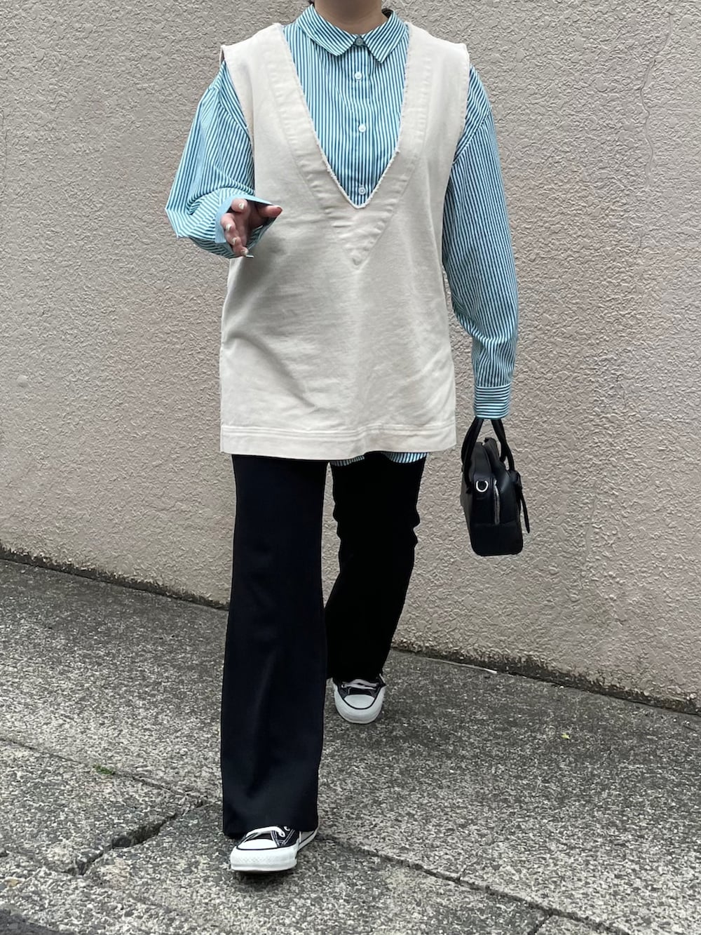 ホワイト系のベスト、ブラック系のボストンバッグ、ブラック系のスニーカーを着用したレディースの春コーディネートの3枚目の写真