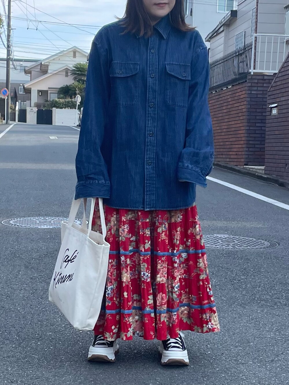 レッド系のスカート、ホワイト系のトートバッグ、ブラック系のスニーカーを着用したレディースの冬コーディネートの2枚目の写真