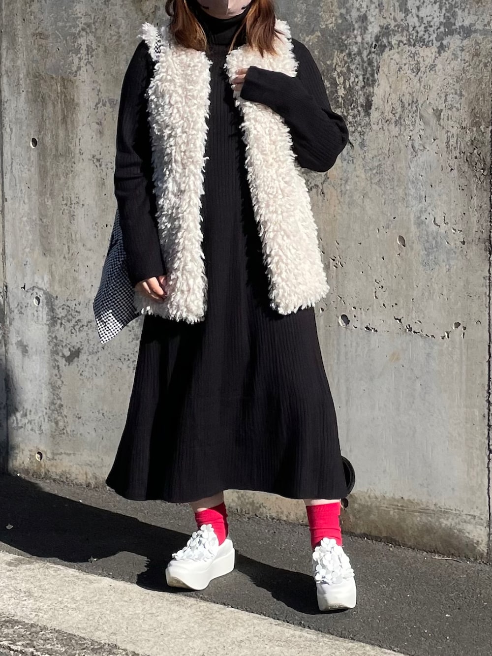 ホワイト系のベスト、ブラック系のワンピースを着用したレディースの冬コーディネートの3枚目の写真