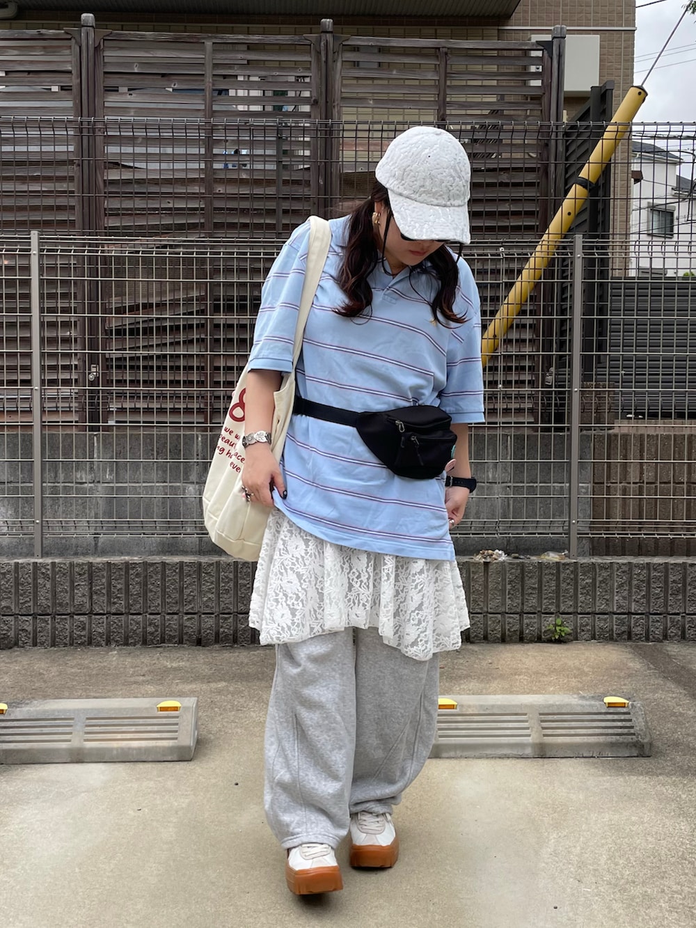 ブルー系のポロシャツ、ブラック系のボディバッグ/ウエストポーチ、ホワイト系のスニーカーを着用したレディースの春コーディネートの2枚目の写真