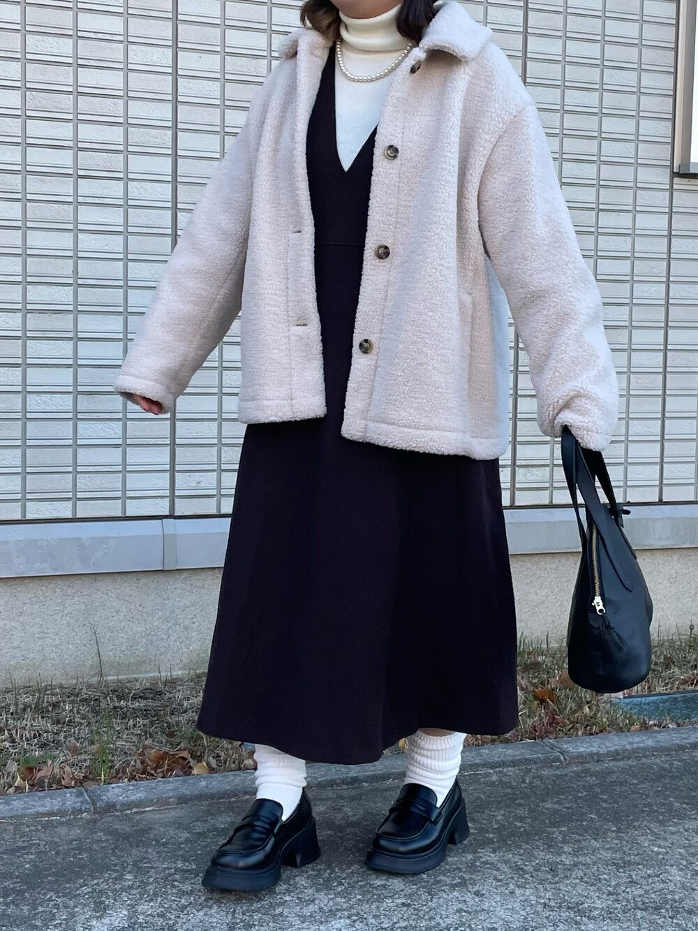 ホワイト系のジャケット/アウター、ブラック系のボストンバッグを着用したレディースの冬コーディネートの2枚目の写真