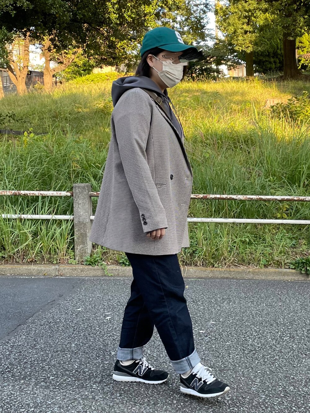 グレー系のパーカー、ブルー系のデニムパンツ、ブルー系のスニーカーを着用したレディースの秋コーディネートの3枚目の写真