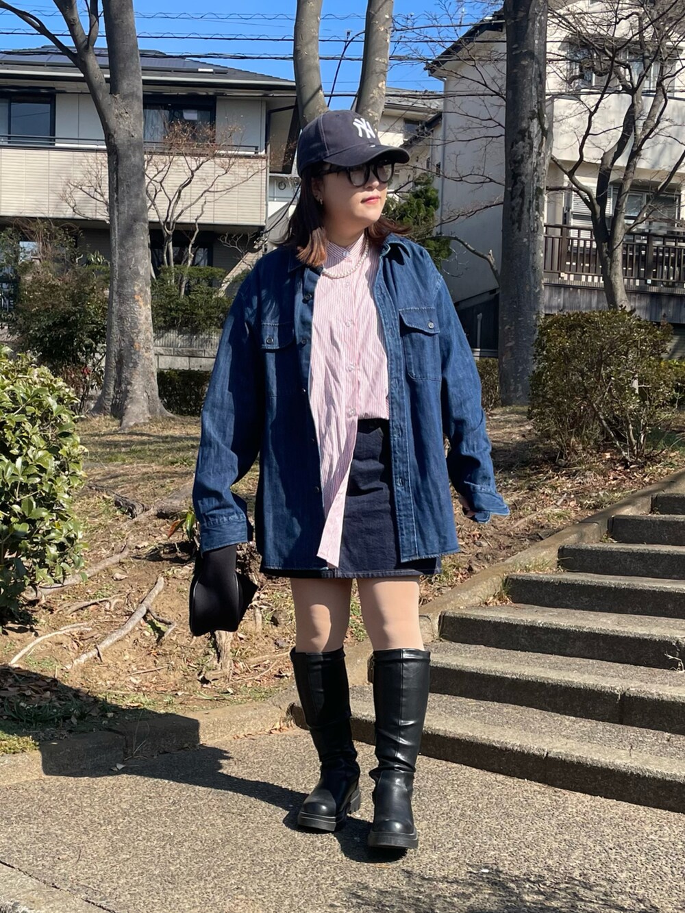 レッド系のシャツ/ブラウス、ブルー系のデニムスカート、ブラック系のハンドバッグを着用したレディースの冬コーディネートの2枚目の写真