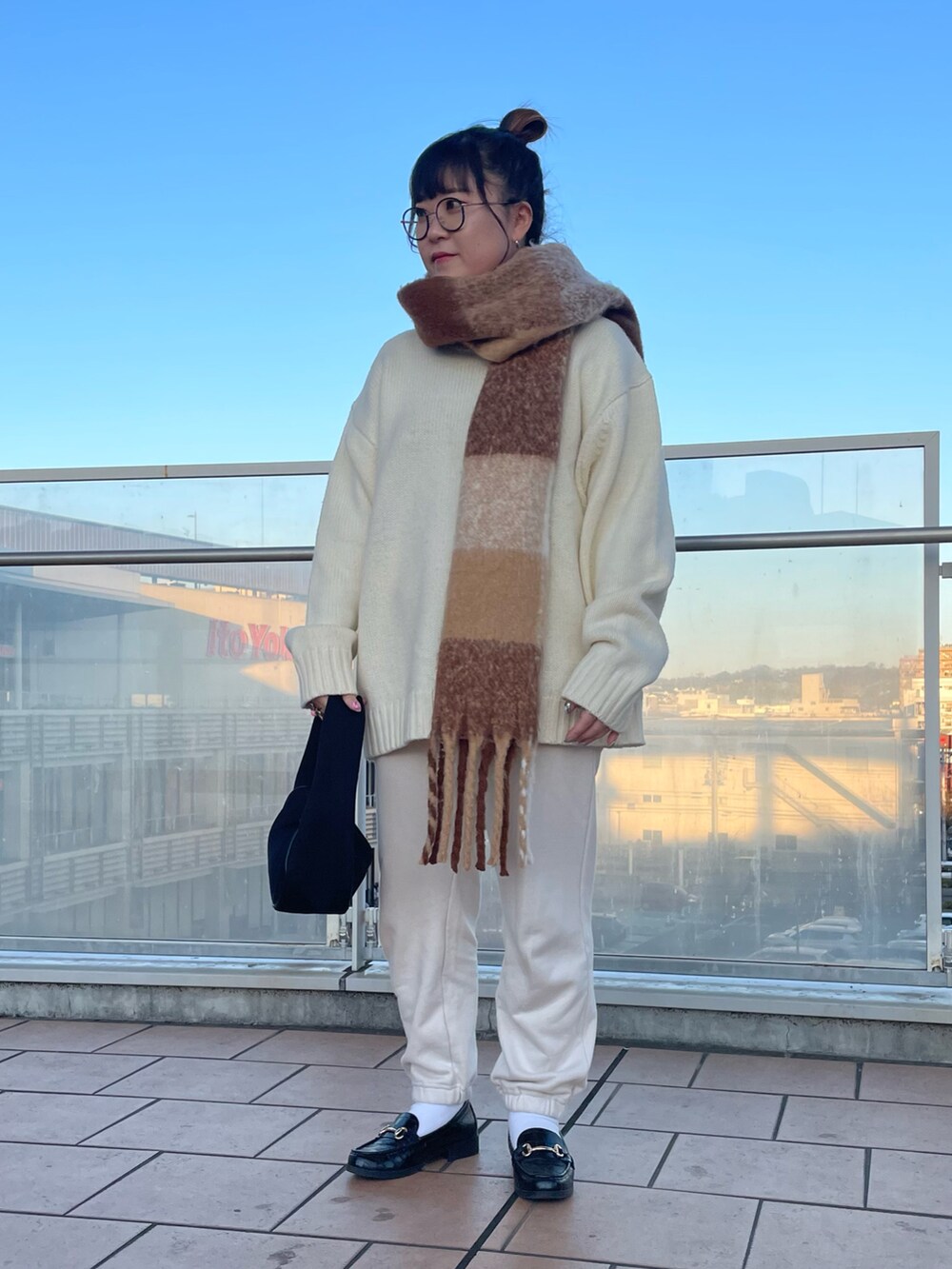 ブラック系のハンドバッグ、ホワイト系のスウェットパンツ、ブラック系のローファーを着用したレディースの冬コーディネートの2枚目の写真