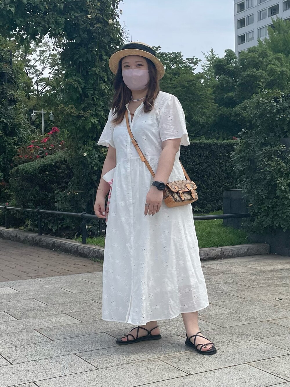 ホワイト系のトートバッグ、ブラック系のハットを着用したレディースの夏コーディネートの2枚目の写真