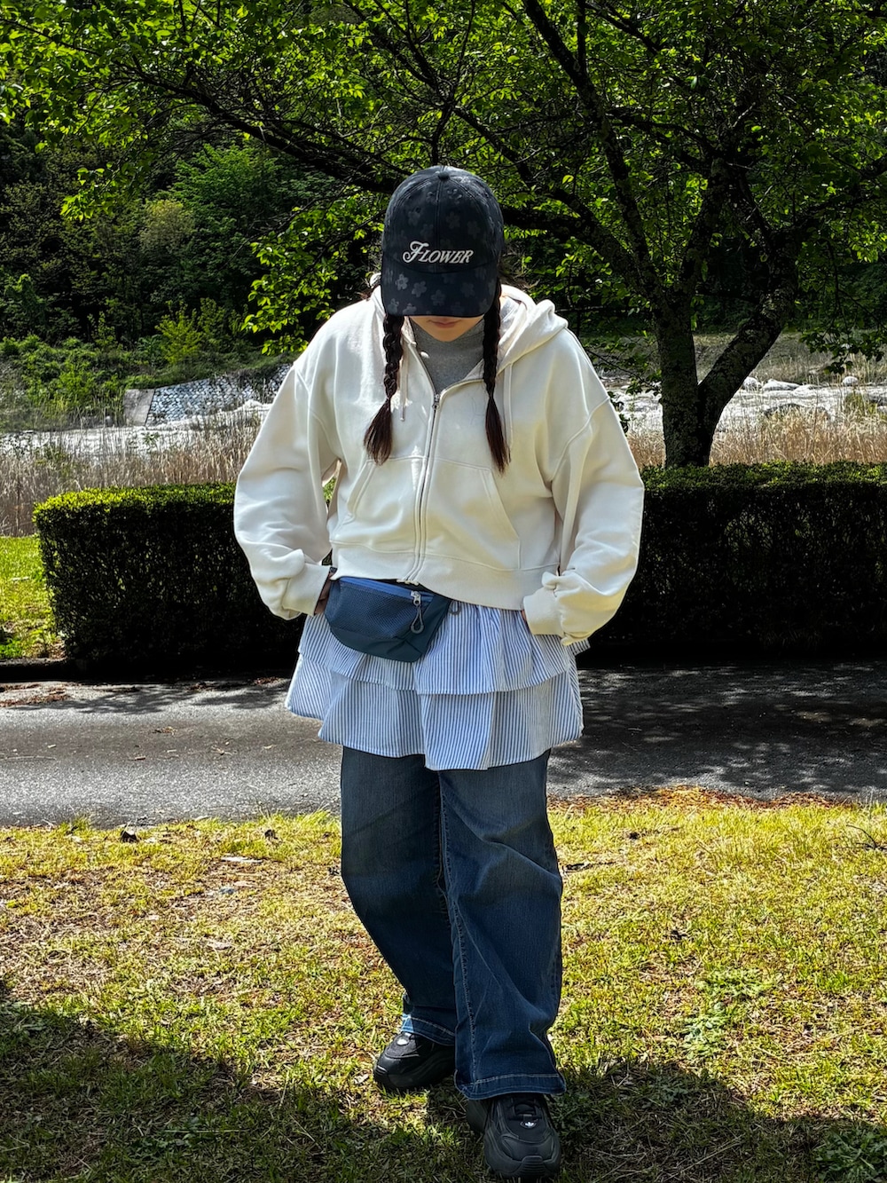 ブラック系のスニーカー、ブルー系のボディバッグ/ウエストポーチ、ブラック系のキャップを着用したレディースの春コーディネートの2枚目の写真