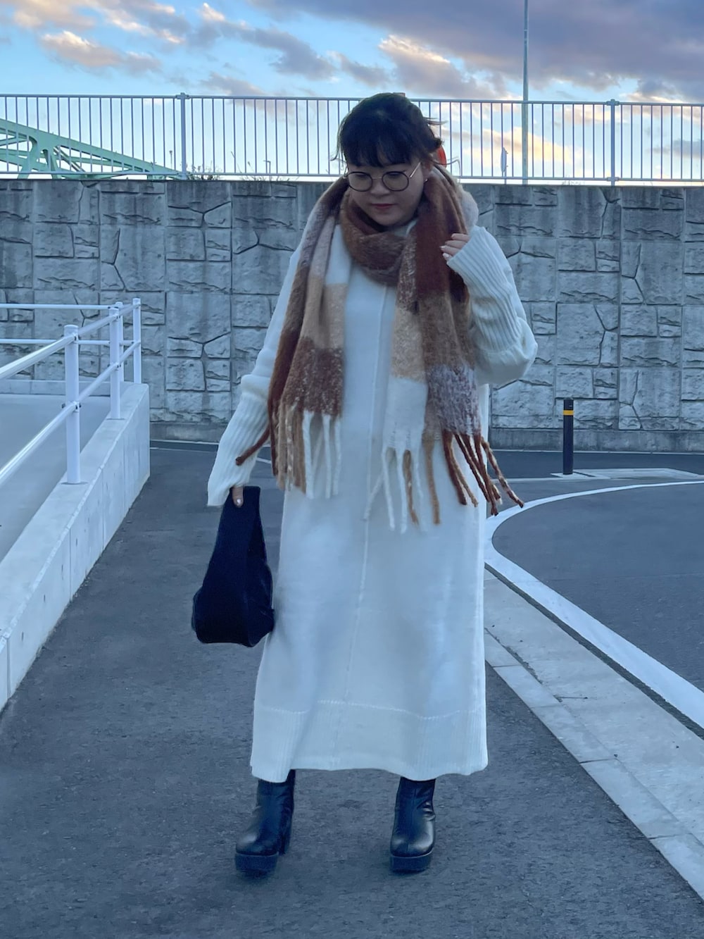 ホワイト系のワンピース、ブラック系のハンドバッグ、ホワイト系のマフラーを着用したレディースの冬コーディネートの2枚目の写真