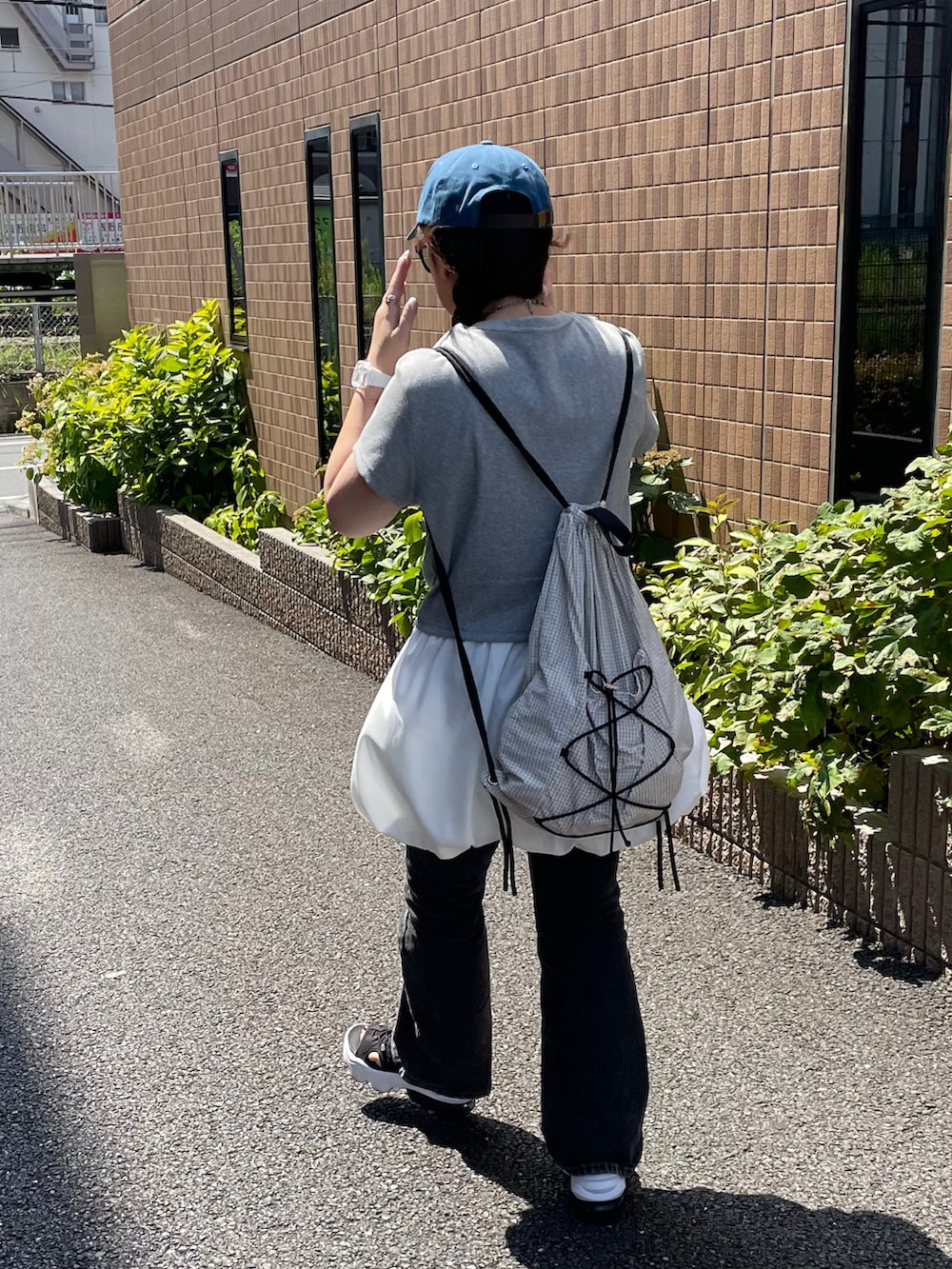 ブラック系のサンダル、ホワイト系のバックパック/リュック、グレー系のTシャツ/カットソーを着用したレディースの秋コーディネートの2枚目の写真