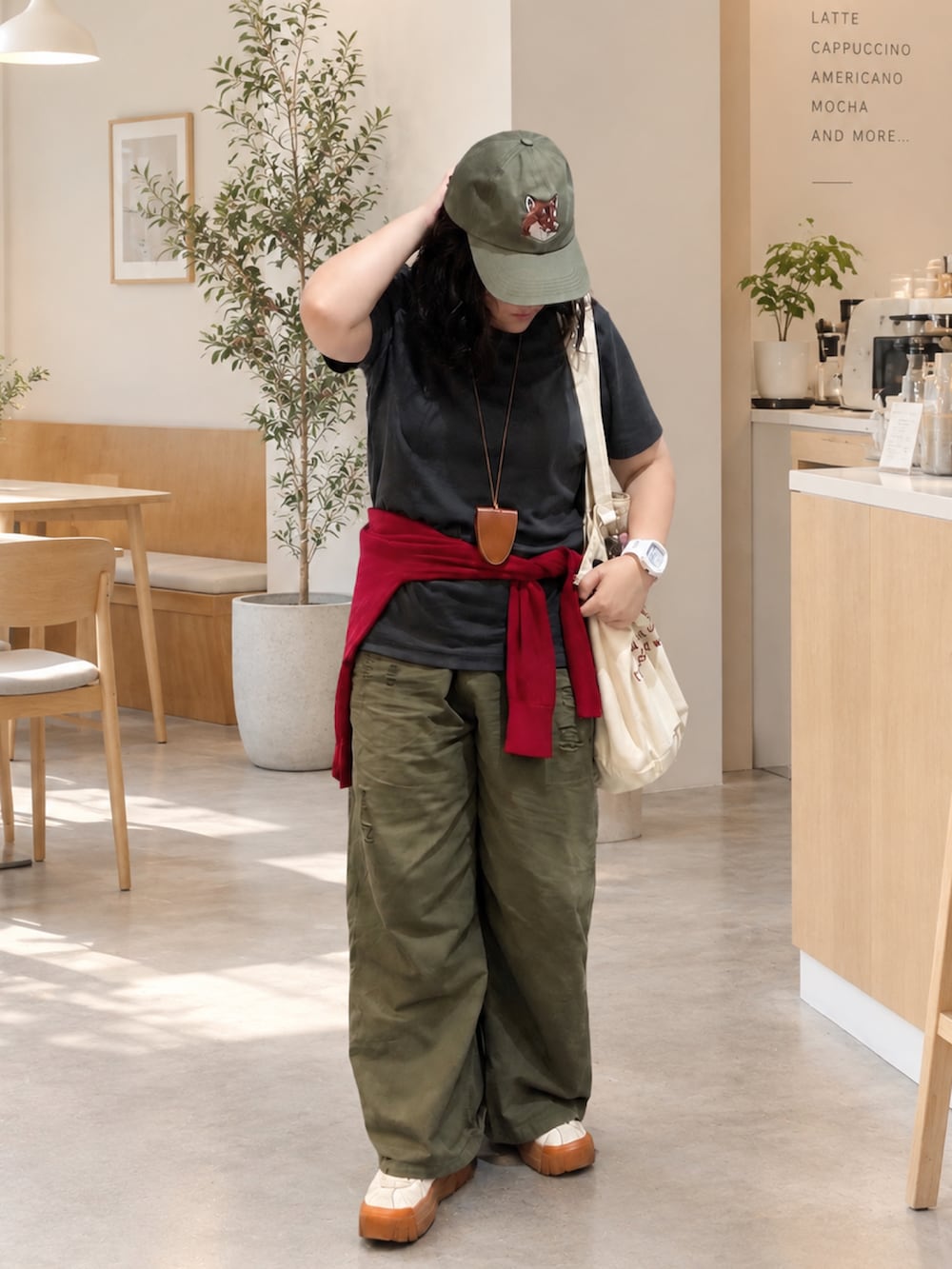 グリーン系のカーゴパンツ、ホワイト系のスニーカー、ベージュ系のトートバッグを着用したレディースの秋コーディネートの2枚目の写真