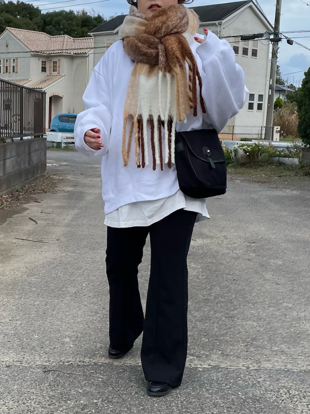 ブラック系のショルダーバッグ、ブラック系のパンツ、ホワイト系のマフラーを着用したレディースの冬コーディネートの2枚目の写真