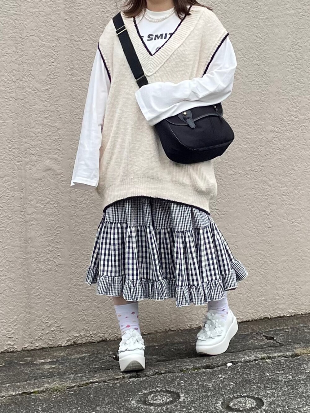 ホワイト系のベスト、ブラック系のショルダーバッグを着用したレディースの秋コーディネートの3枚目の写真