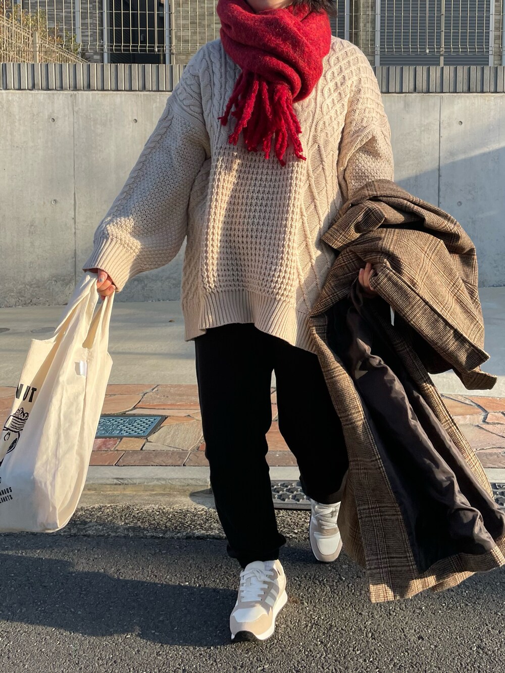 ブラウン系のチェスターコート、ホワイト系のニット/セーター、ホワイト系のスウェットパンツを着用したレディースの冬コーディネートの2枚目の写真