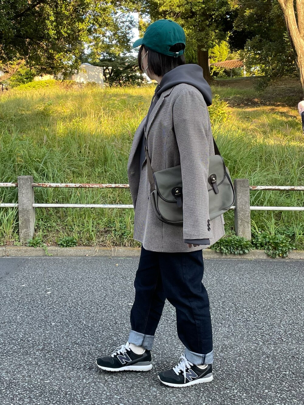 グレー系のパーカー、ブルー系のデニムパンツ、ブルー系のスニーカーを着用したレディースの秋コーディネートの2枚目の写真