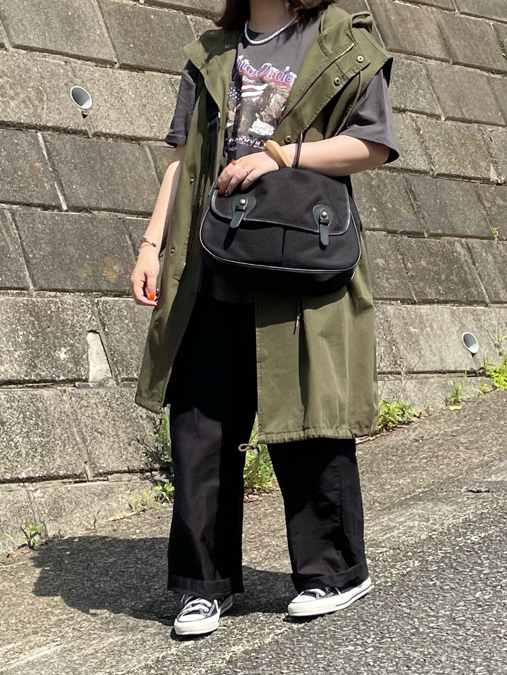 グレー系のTシャツ/カットソー、グリーン系のベスト、ブラック系のスニーカーを着用したレディースの春コーディネートの3枚目の写真