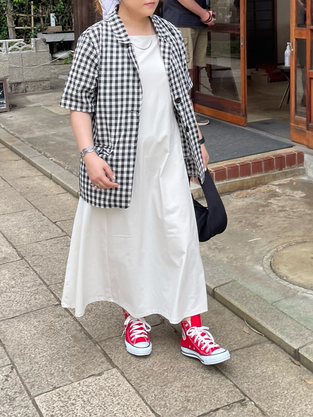 レッド系のスニーカー、ブラック系のハンドバッグ、ホワイト系のワンピース/ドレスを着用したレディースの夏コーディネートの2枚目の写真
