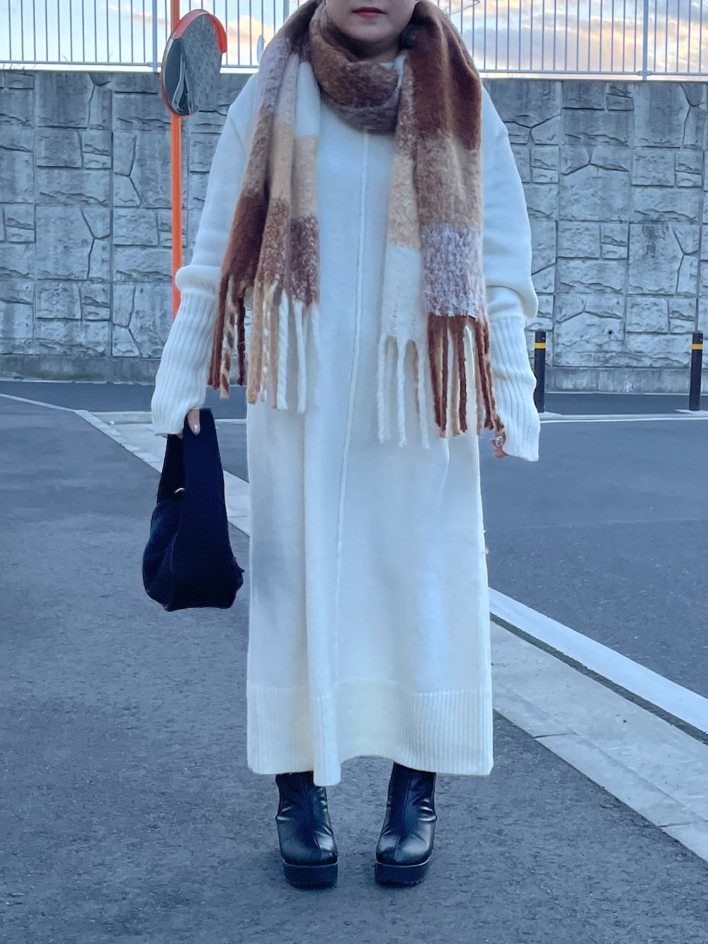 ホワイト系のワンピース、ブラック系のハンドバッグ、ホワイト系のマフラーを着用したレディースの冬コーディネートの3枚目の写真