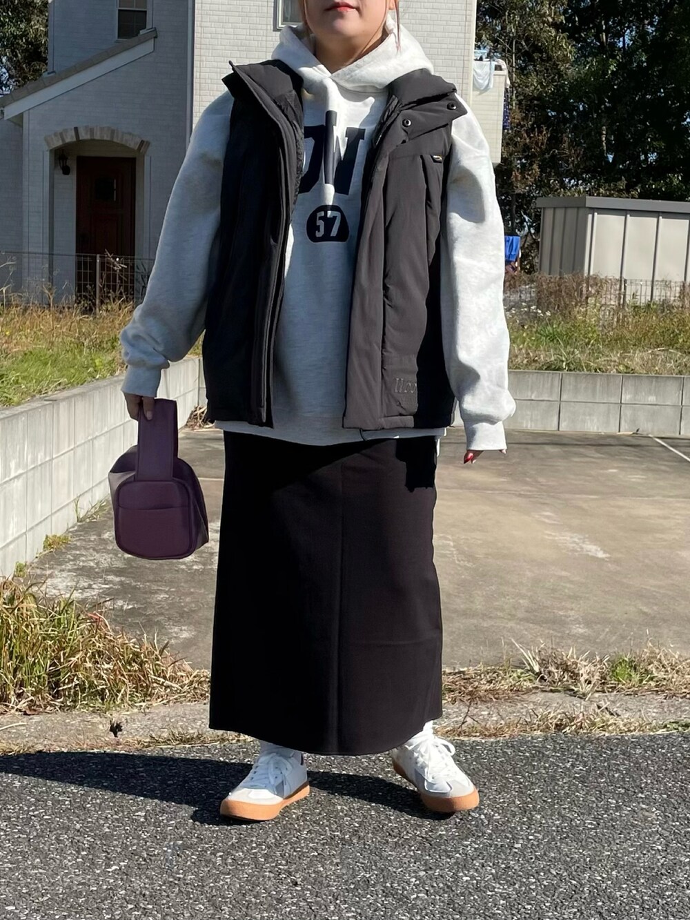 ブラック系のダウンベスト、ベージュ系のパーカー、ピンク系のボストンバッグを着用したレディースの冬コーディネートの3枚目の写真