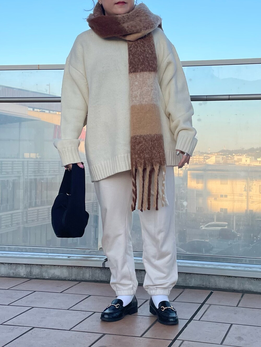 ブラック系のハンドバッグ、ホワイト系のスウェットパンツ、ブラック系のローファーを着用したレディースの冬コーディネートの3枚目の写真