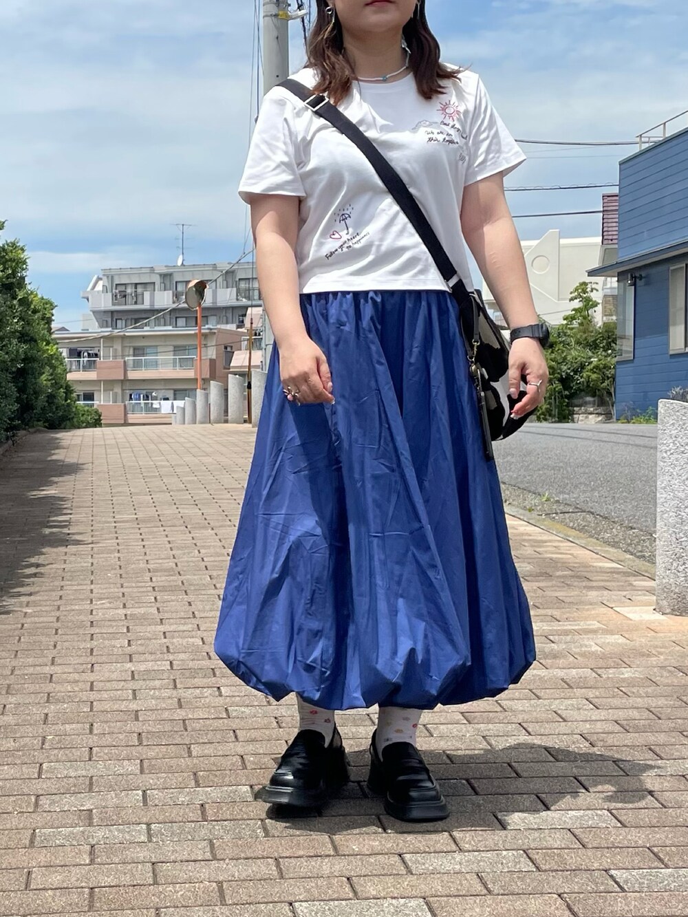 ブルー系のスカート、ブラック系のショルダーバッグを着用したレディースの夏コーディネートの2枚目の写真