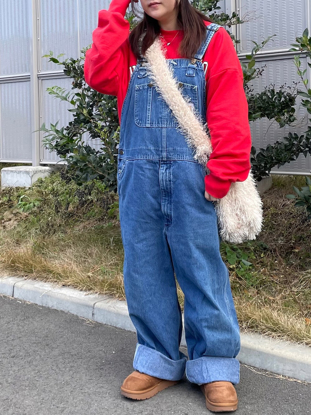 レッド系のスウェット、ブルー系のサロペット/オーバーオール、ベージュ系のシューズを着用したレディースの冬コーディネートの2枚目の写真