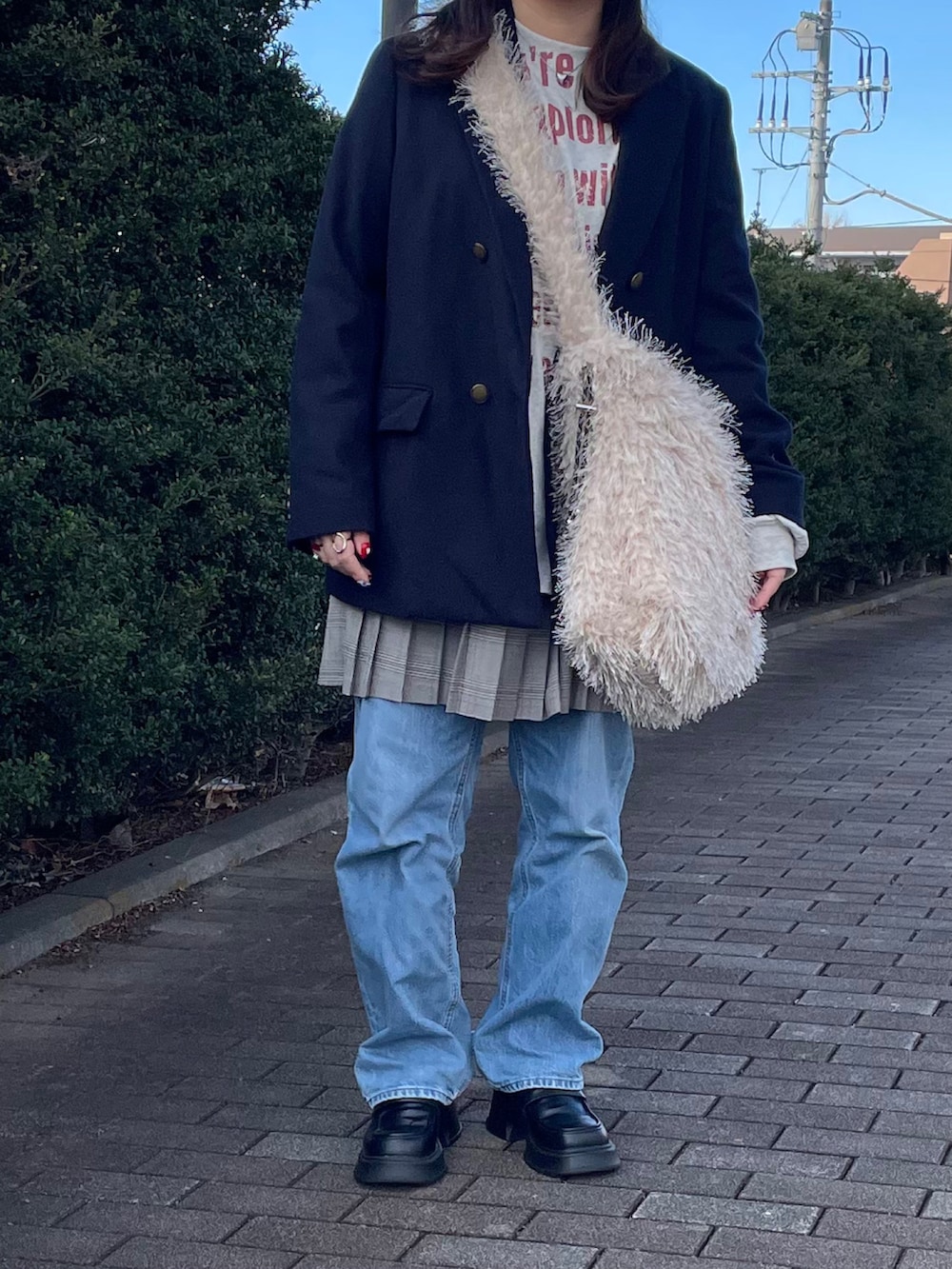 ベージュ系のTシャツ/カットソー、グレー系のスカート、ベージュ系のショルダーバッグを着用したレディースの冬コーディネートの2枚目の写真