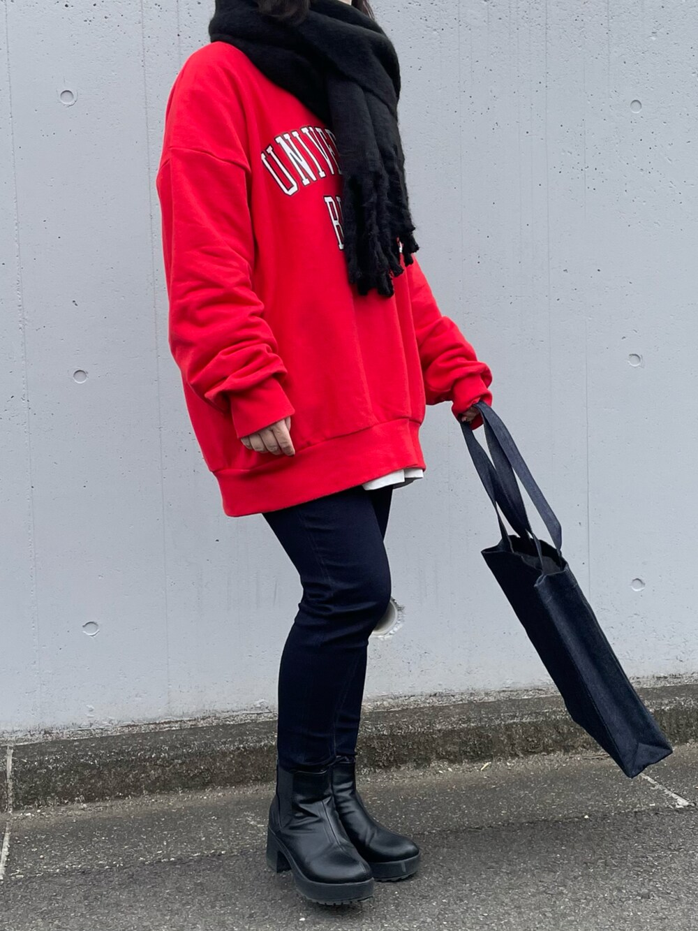 レッド系のスウェット、ブルー系のパンツ、ブルー系のトートバッグを着用したレディースの冬コーディネートの2枚目の写真