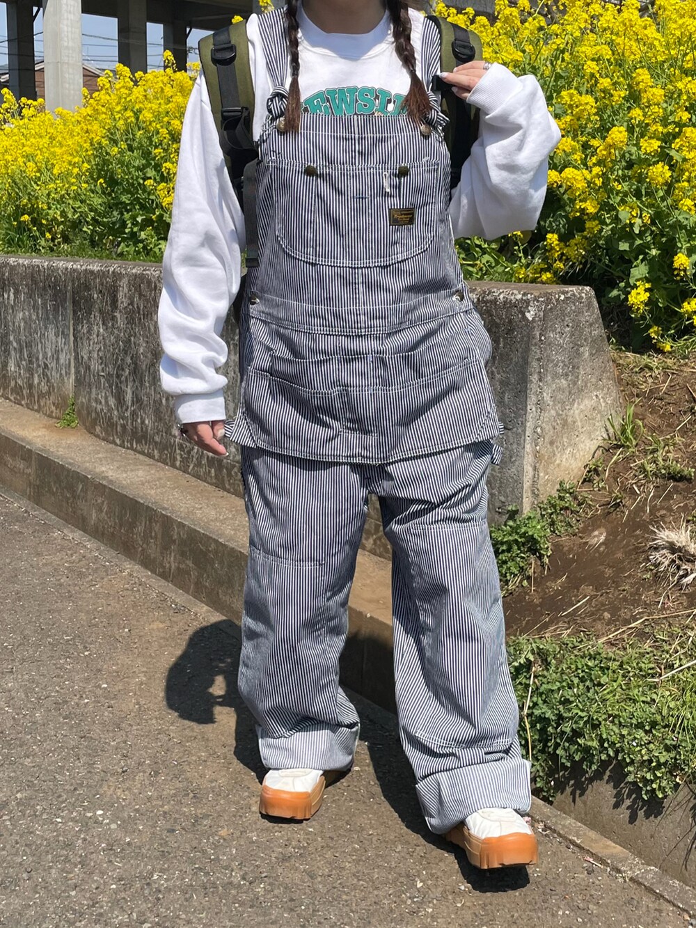 ホワイト系のスウェット、ブルー系のサロペット/オーバーオール、グリーン系のバックパック/リュックを着用したレディースの春コーディネートの3枚目の写真