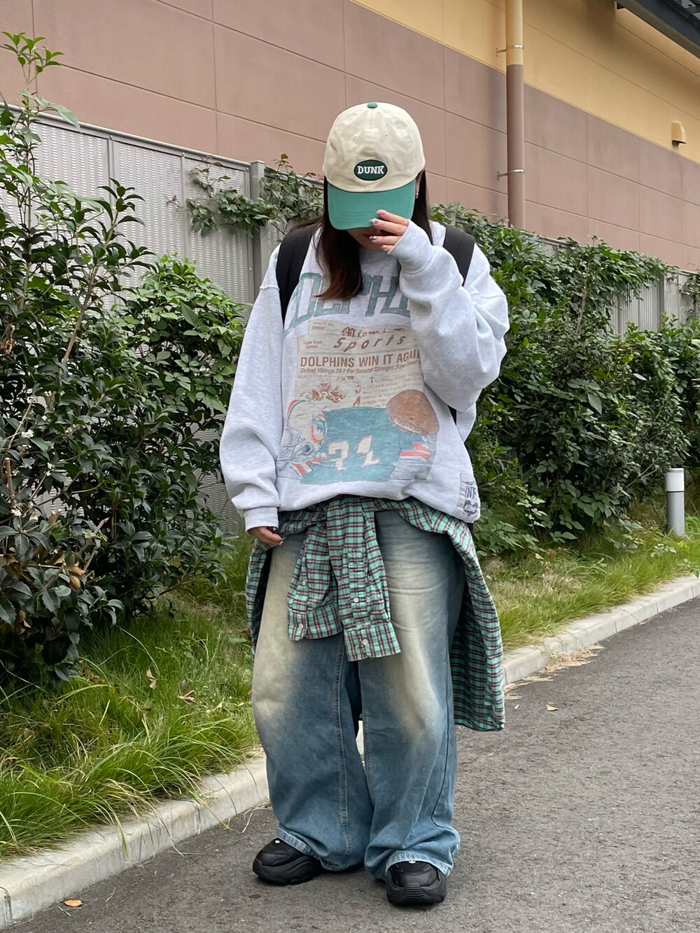 グレー系のスウェット、ブルー系のデニムパンツ、ブラック系のスニーカーを着用したレディースの秋コーディネートの2枚目の写真