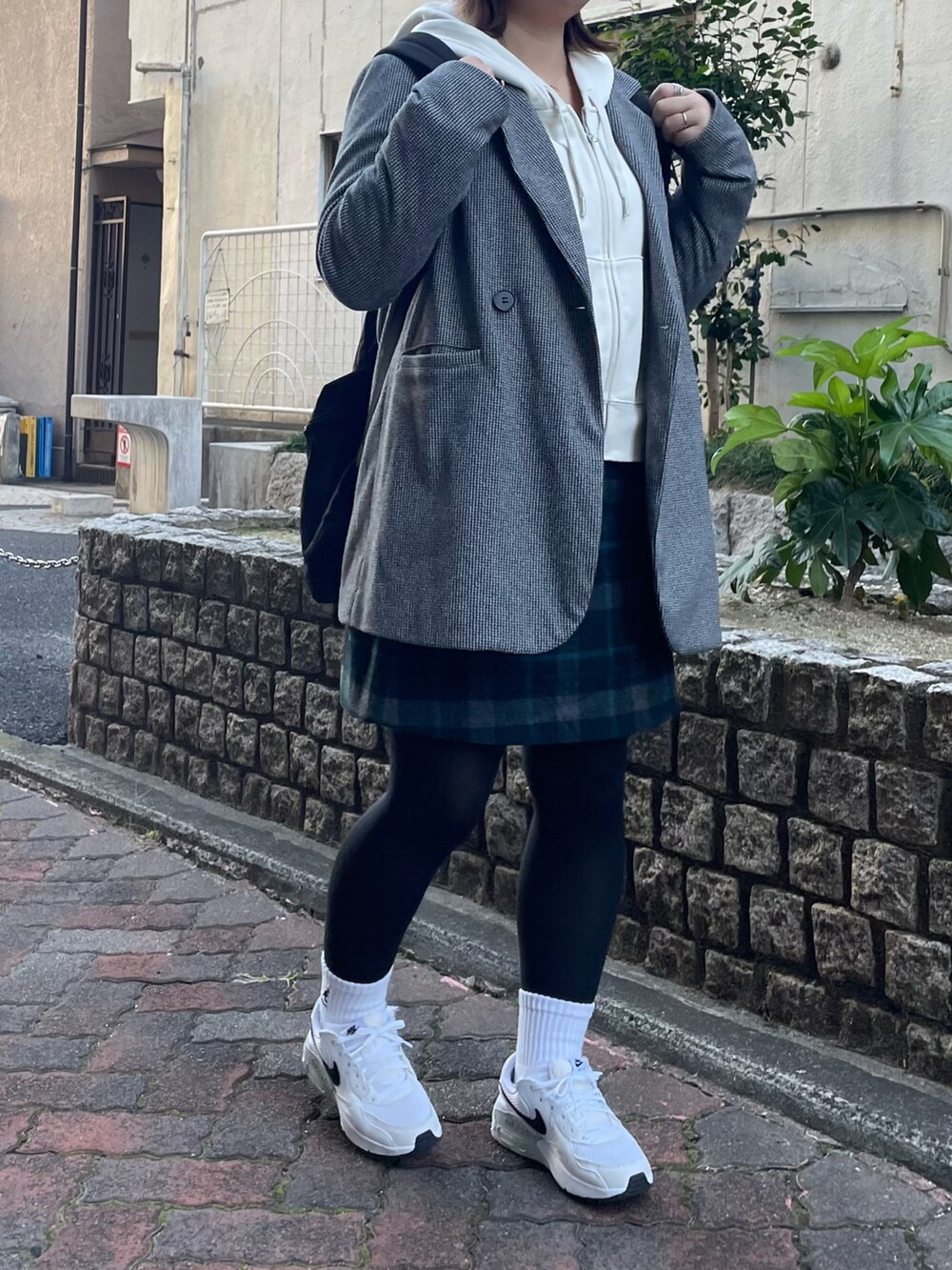 ブラック系のテーラードジャケット、ホワイト系のスニーカー、ブラック系のバックパック/リュックを着用したレディースの冬コーディネートの2枚目の写真