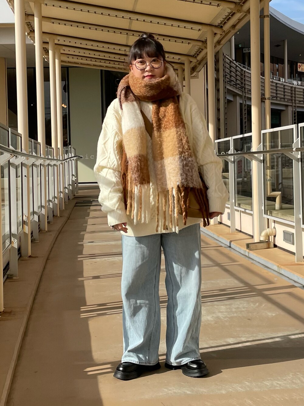 ベージュ系のショルダーバッグ、ホワイト系のマフラーを着用したレディースの冬コーディネートの2枚目の写真