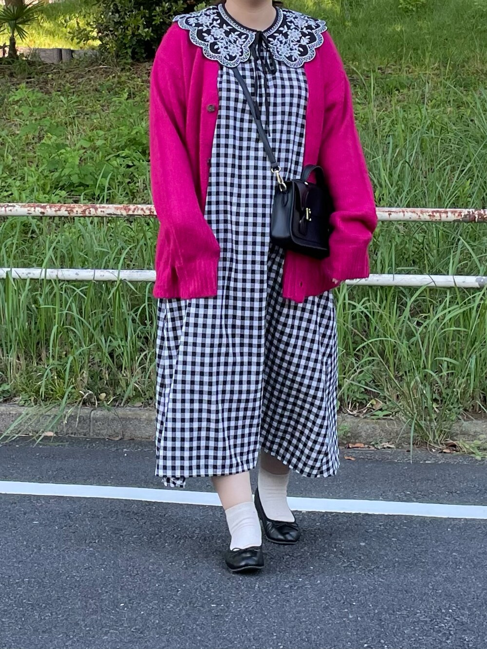 ブラック系のワンピース、ピンク系のカーディガン/ボレロ、ブラック系のバッグを着用したレディースの秋コーディネートの2枚目の写真