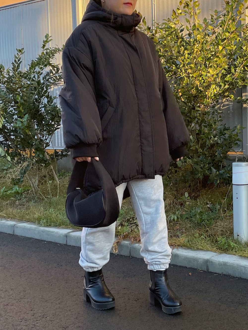 ブラック系のハンドバッグ、ホワイト系のスウェットパンツ、ブラック系のブーツを着用したレディースの冬コーディネートの3枚目の写真