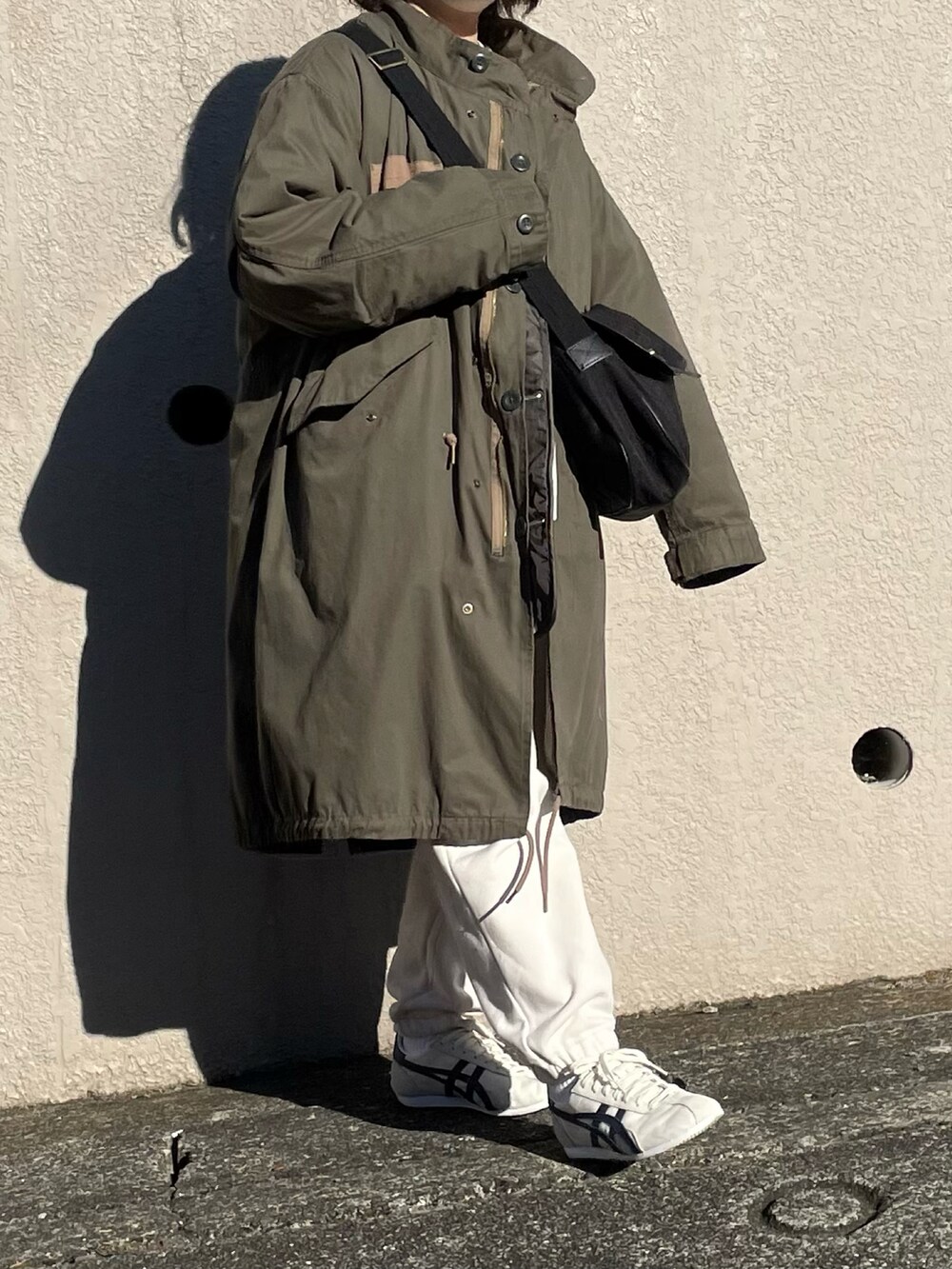 グリーン系のモッズコート、ホワイト系のスウェットパンツ、ホワイト系のスウェットを着用したレディースの冬コーディネートの2枚目の写真