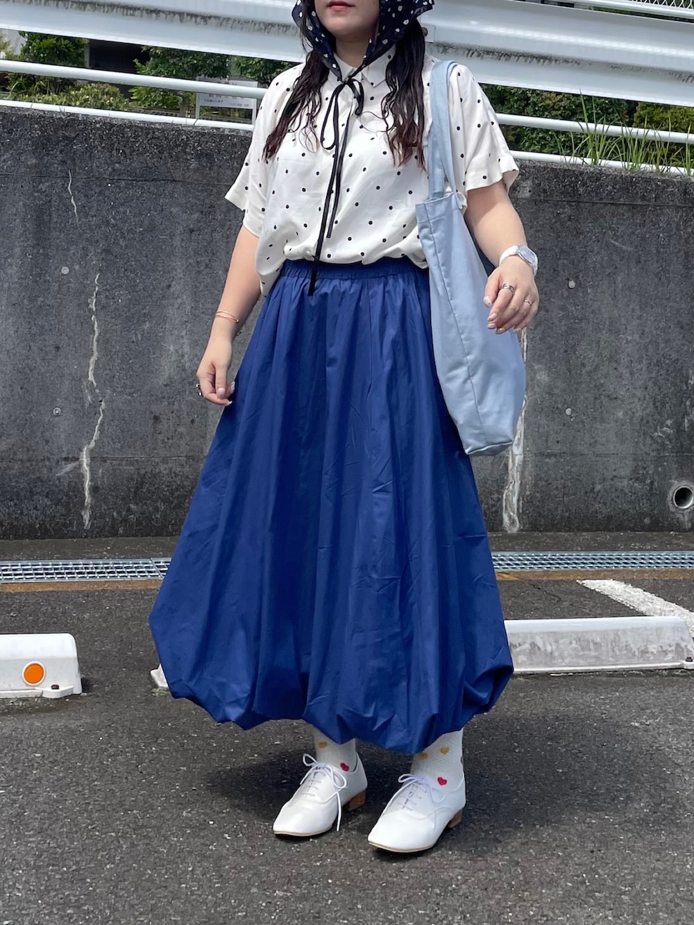 ブルー系のトートバッグ、ブルー系のスカート、ホワイト系のドレスシューズを着用したレディースの夏コーディネートの2枚目の写真