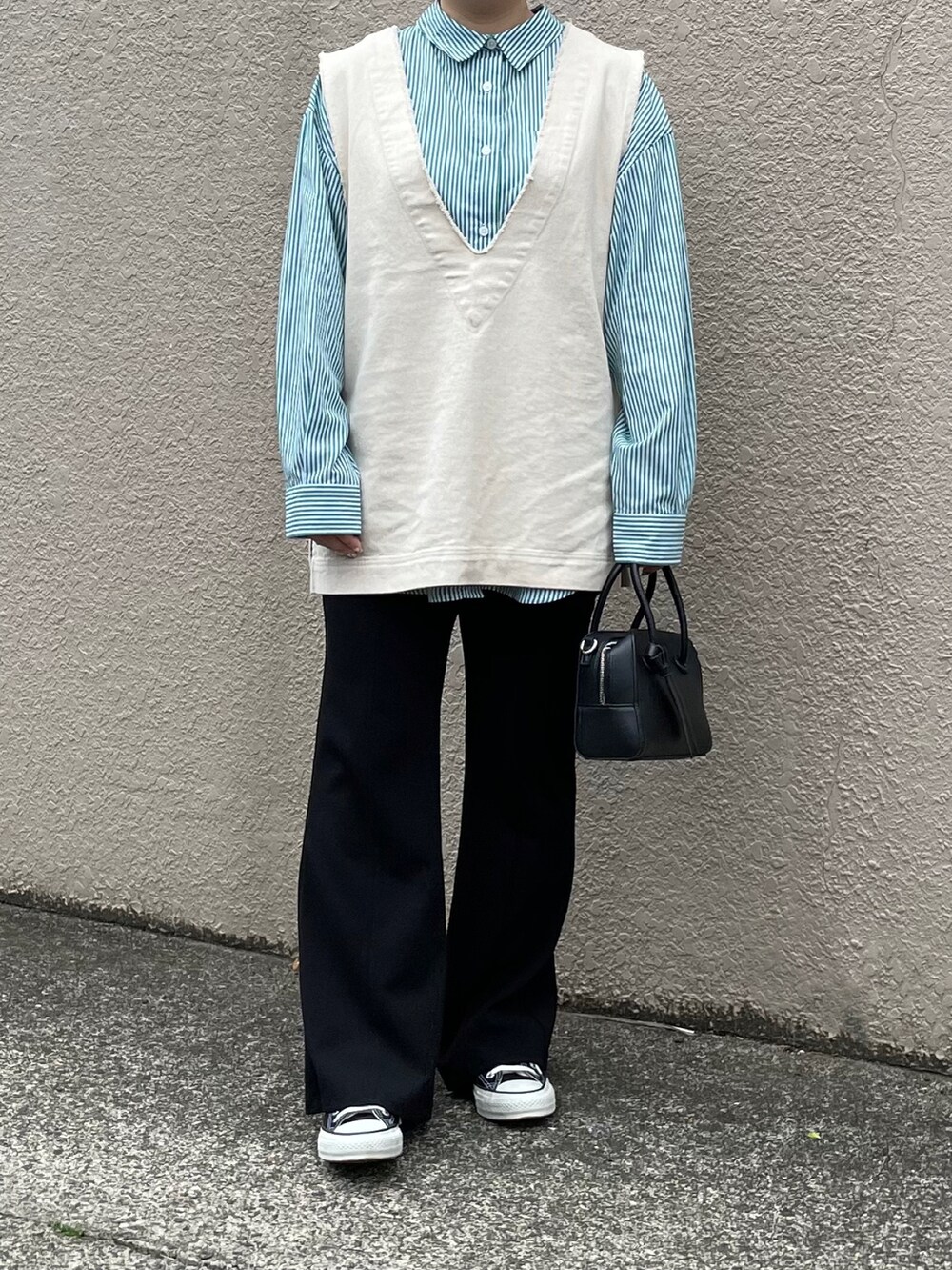 ホワイト系のベスト、ブラック系のボストンバッグ、ブラック系のスニーカーを着用したレディースの春コーディネートの2枚目の写真