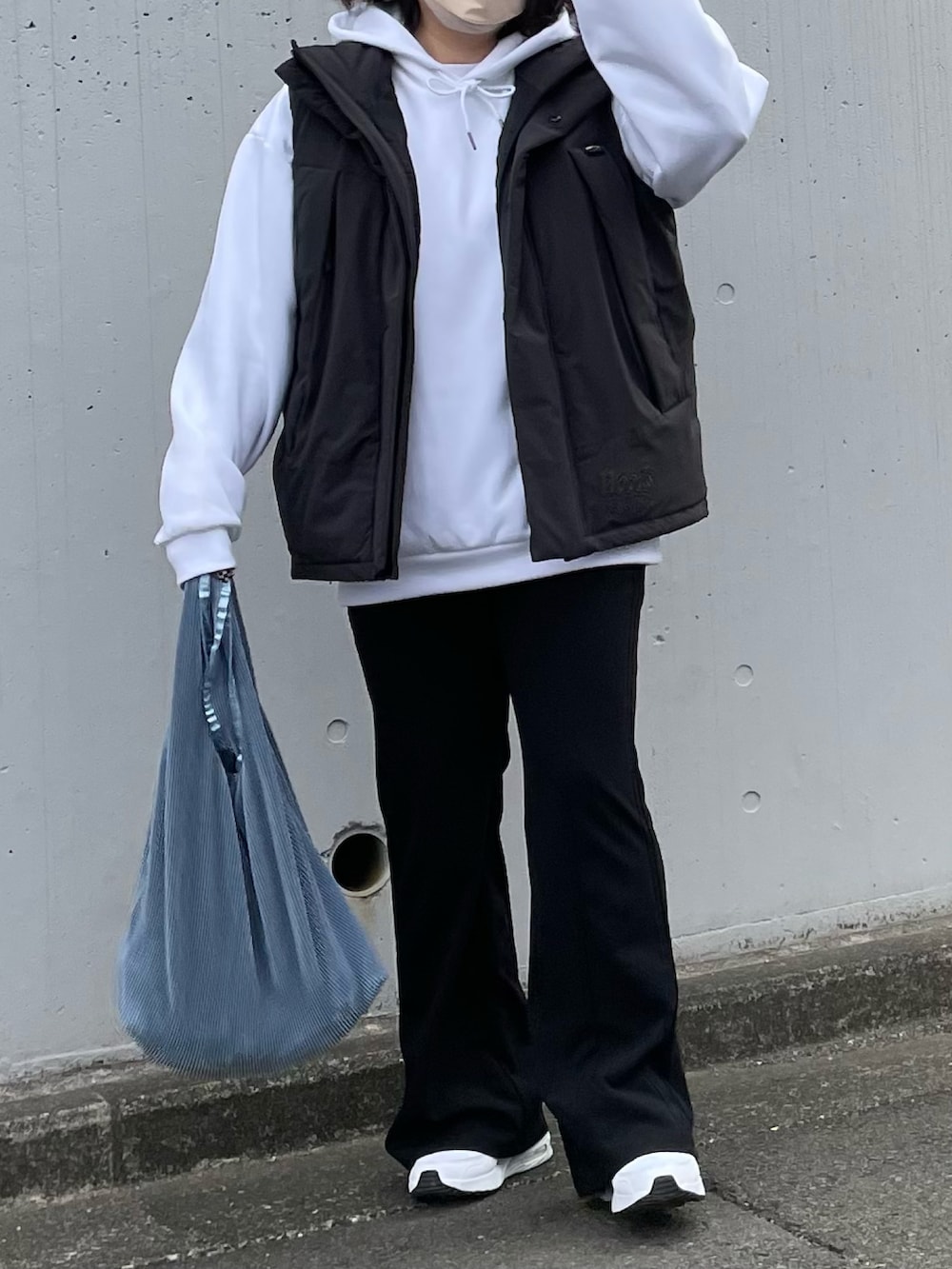 ブラック系のダウンベスト、ホワイト系のパーカー、ブラック系のパンツを着用したレディースの冬コーディネートの2枚目の写真