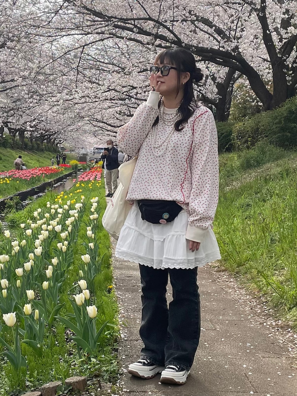 ホワイト系のTシャツ/カットソー、ホワイト系のスカート、ブラック系のスニーカーを着用したレディースの春コーディネートの2枚目の写真