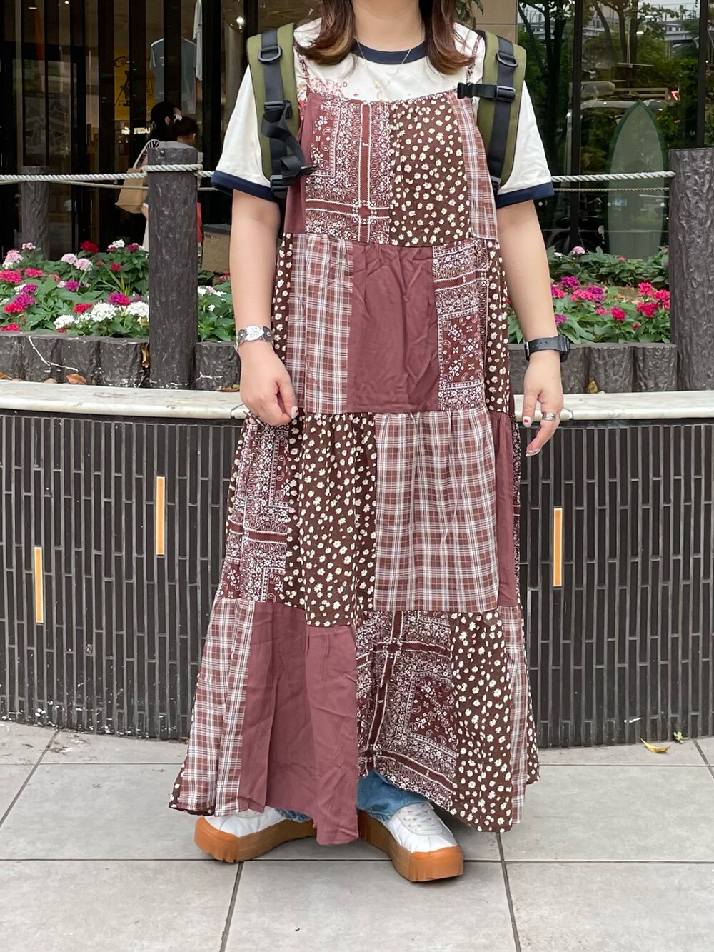 ブラウン系のワンピース、グリーン系のバックパック/リュック、ホワイト系のスニーカーを着用したレディースの夏コーディネートの2枚目の写真