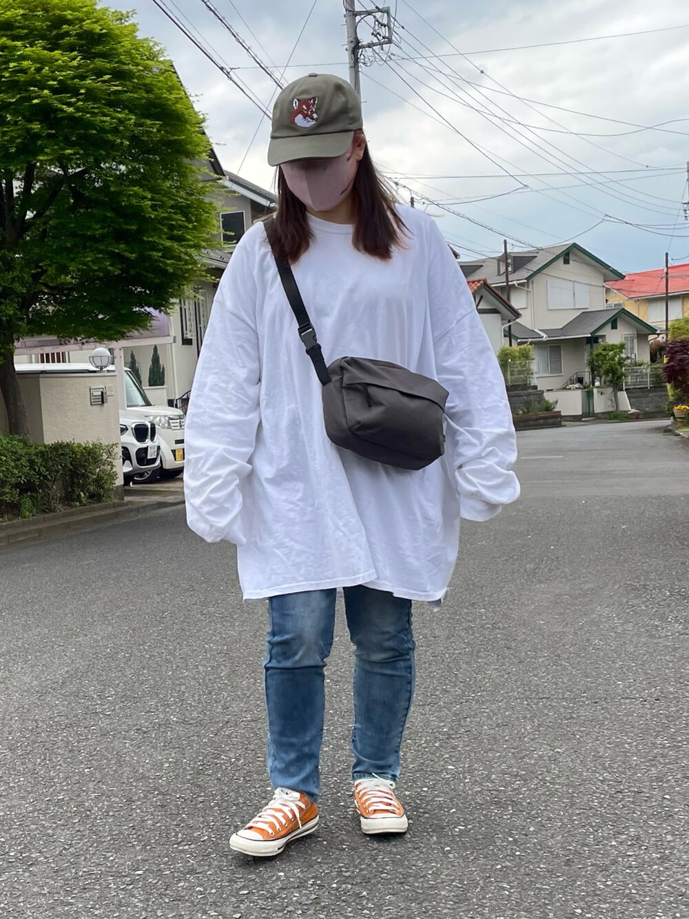 オレンジ系のスニーカー、グリーン系のキャップを着用したレディースの春コーディネートの2枚目の写真