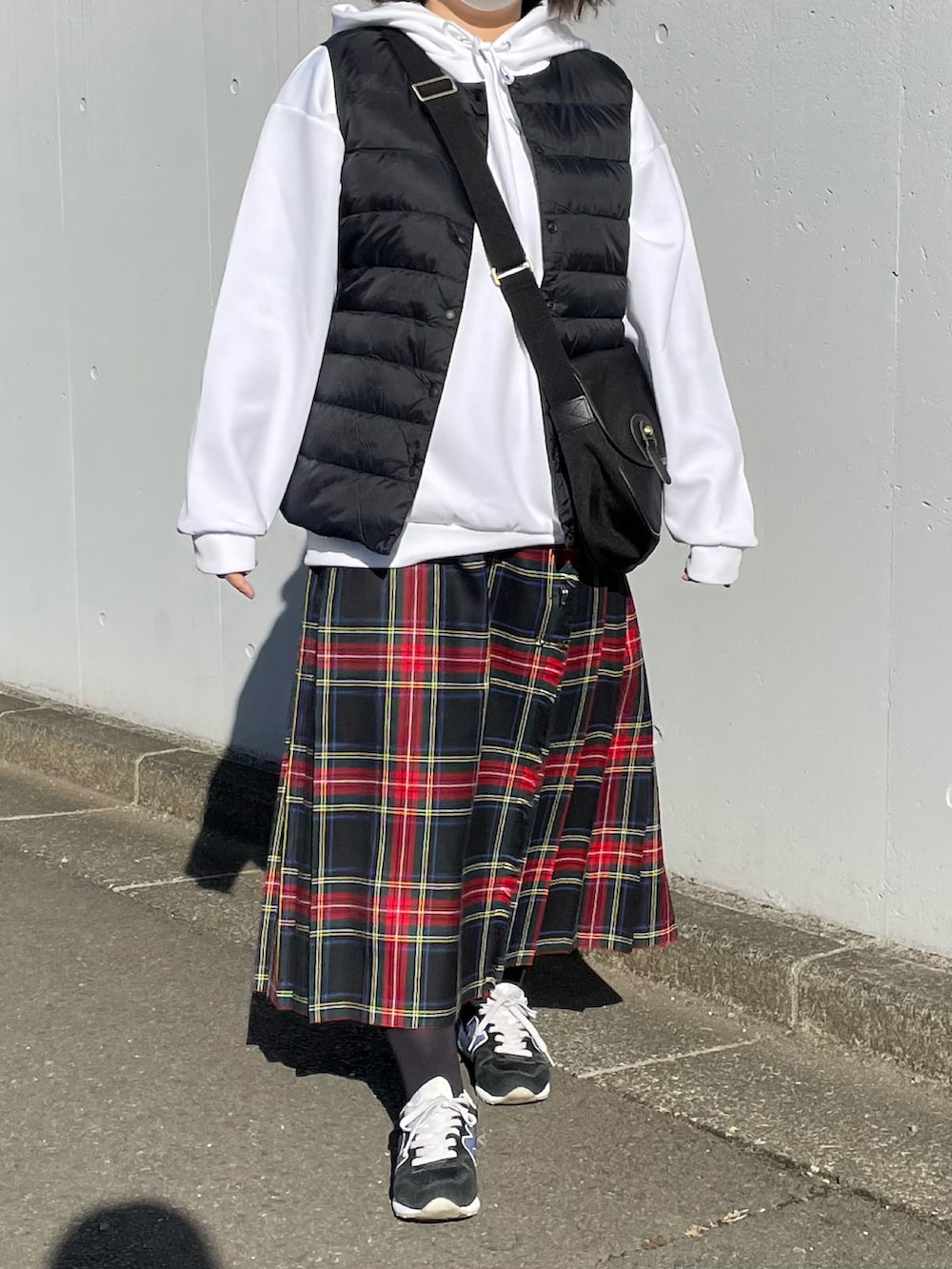 ホワイト系のパーカー、ブラック系のスカート、ブラック系のショルダーバッグを着用したレディースの冬コーディネートの2枚目の写真