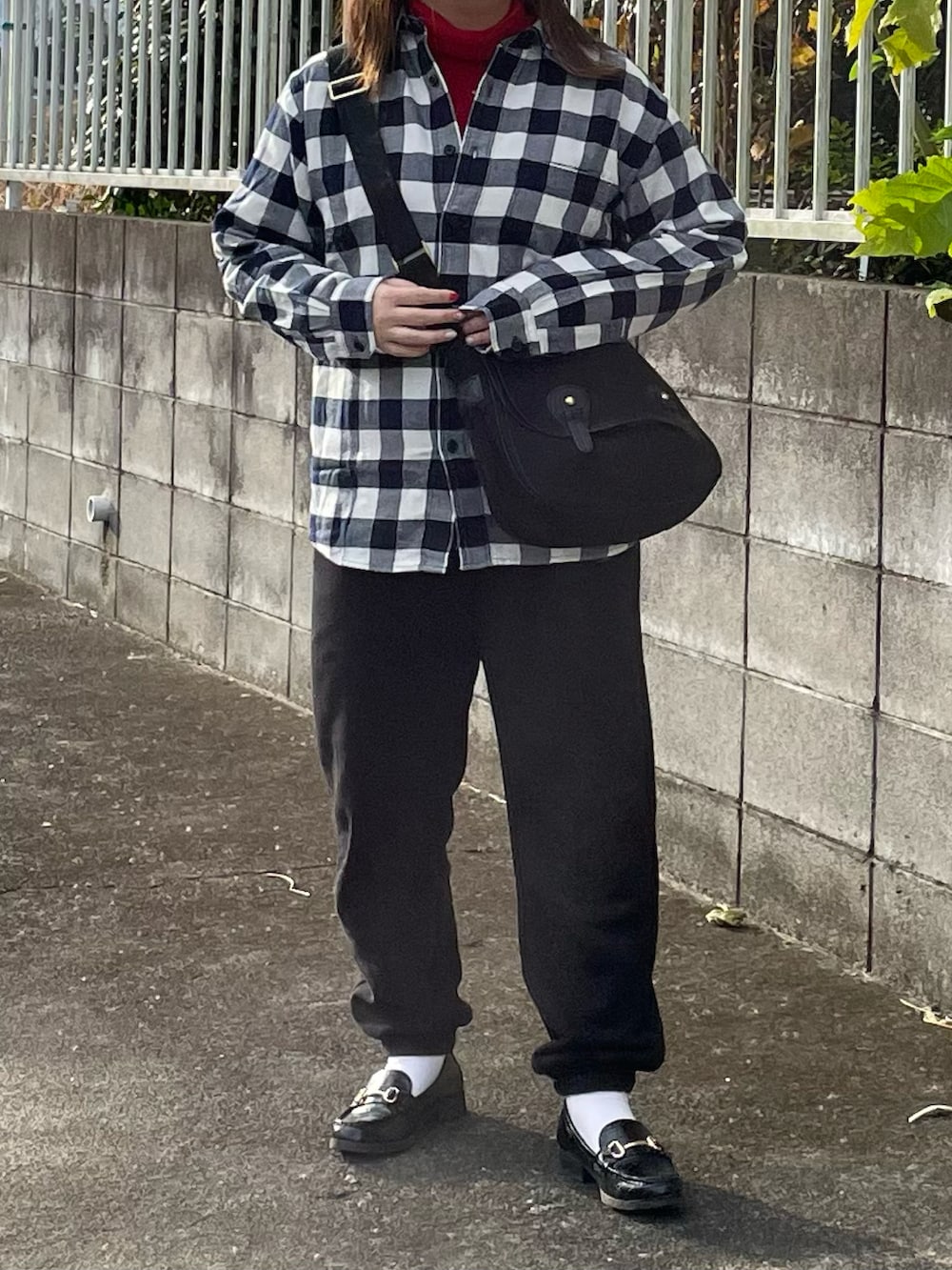 ブルー系のシャツ/ブラウス、レッド系のニット/セーター、ブラック系のショルダーバッグを着用したレディースの冬コーディネートの2枚目の写真