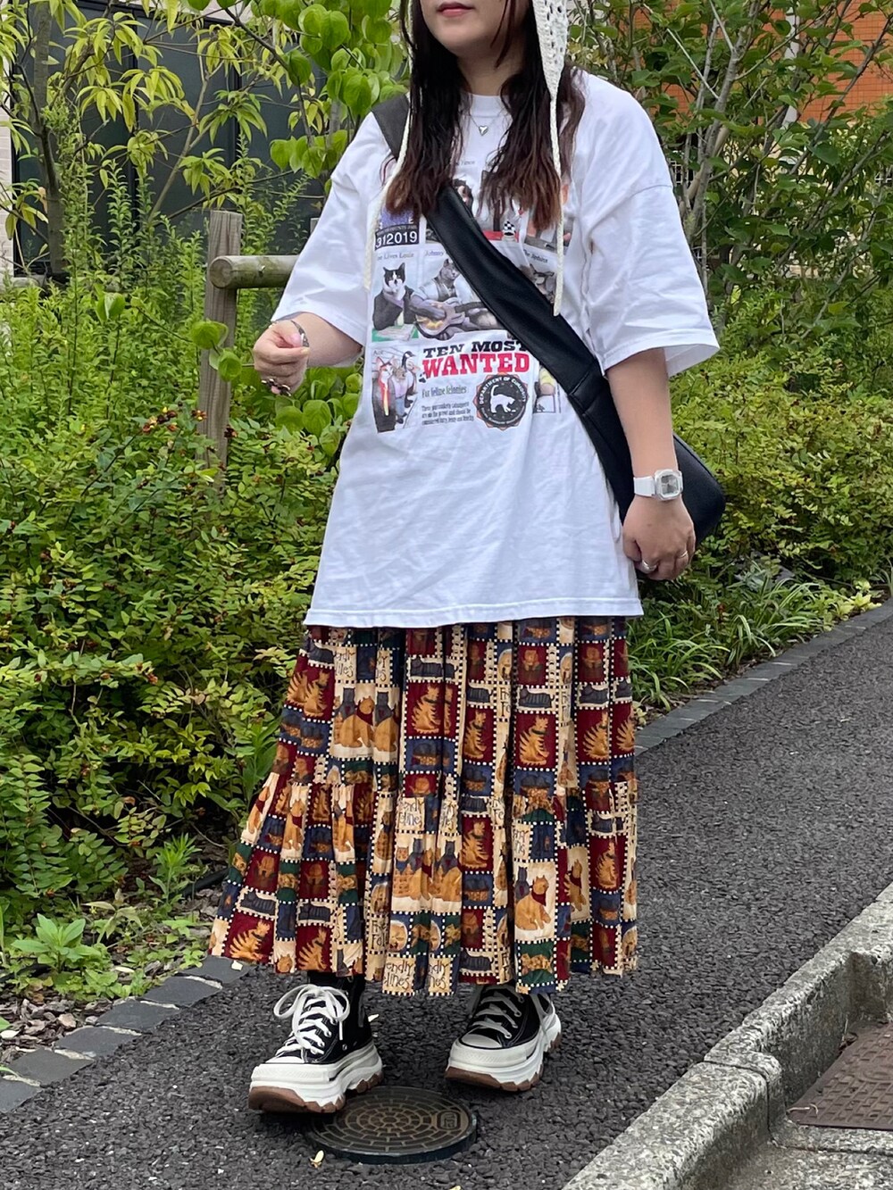 ブラック系のスニーカー、ホワイト系のTシャツ/カットソー、ブラウン系のスカートを着用したレディースの夏コーディネートの3枚目の写真