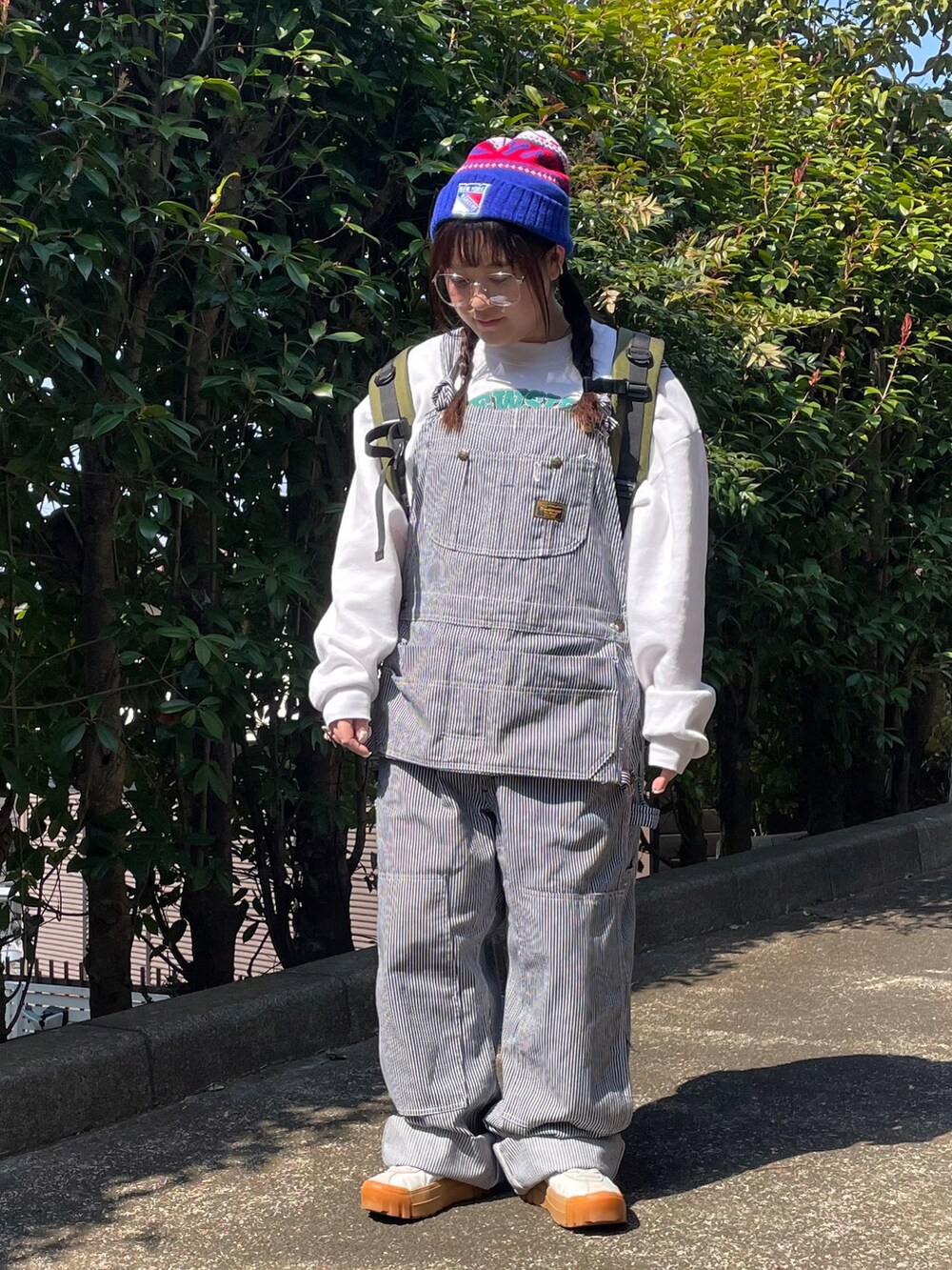 ホワイト系のスウェット、ブルー系のサロペット/オーバーオール、グリーン系のバックパック/リュックを着用したレディースの春コーディネートの2枚目の写真